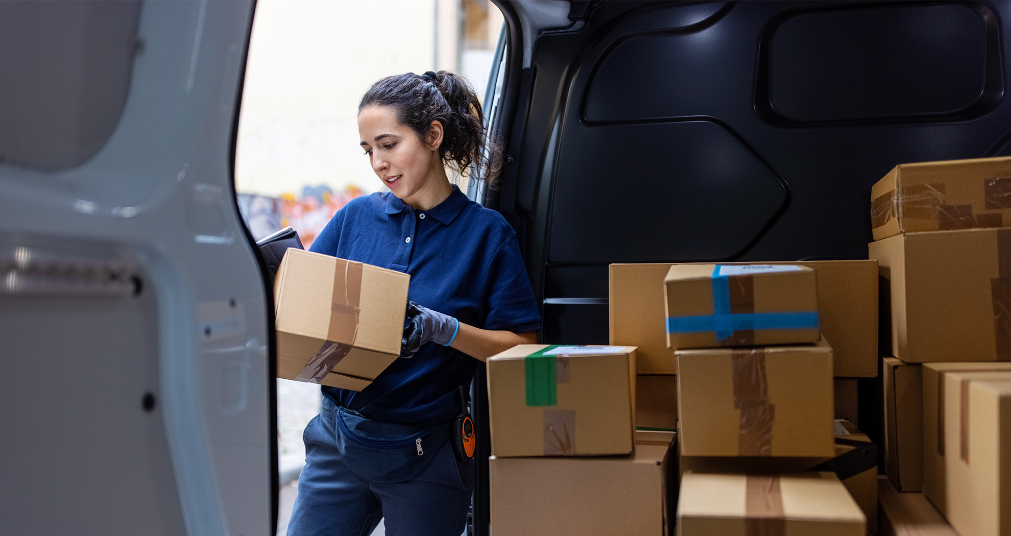 Young woman unloading a transit van while thinking about her carbon footprint.