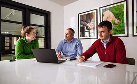 Three office workers sat around a table