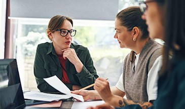 Three oficce workers sat round a table, dicussing how to get started