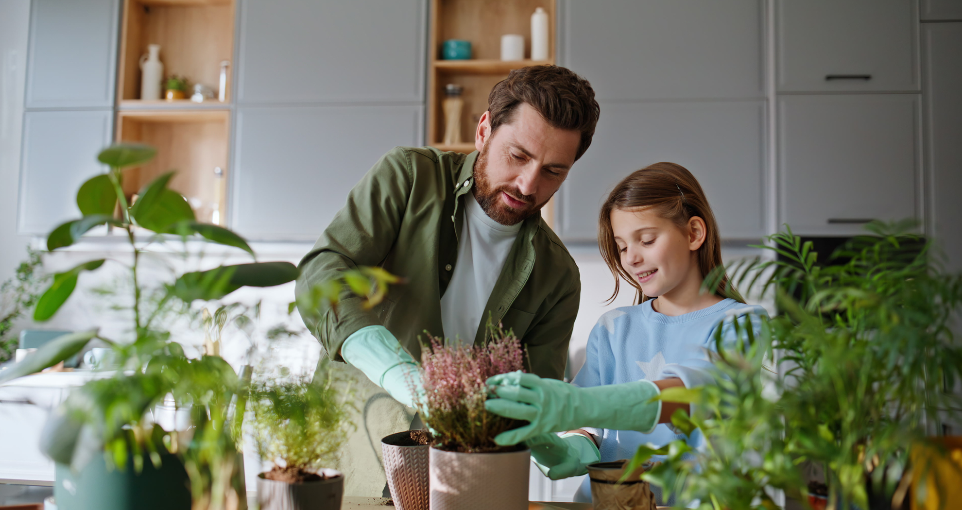 A father and daughter potting plants in their kitchen