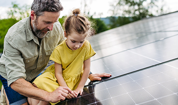 A father and his daughter are sitting looking at solar panels together