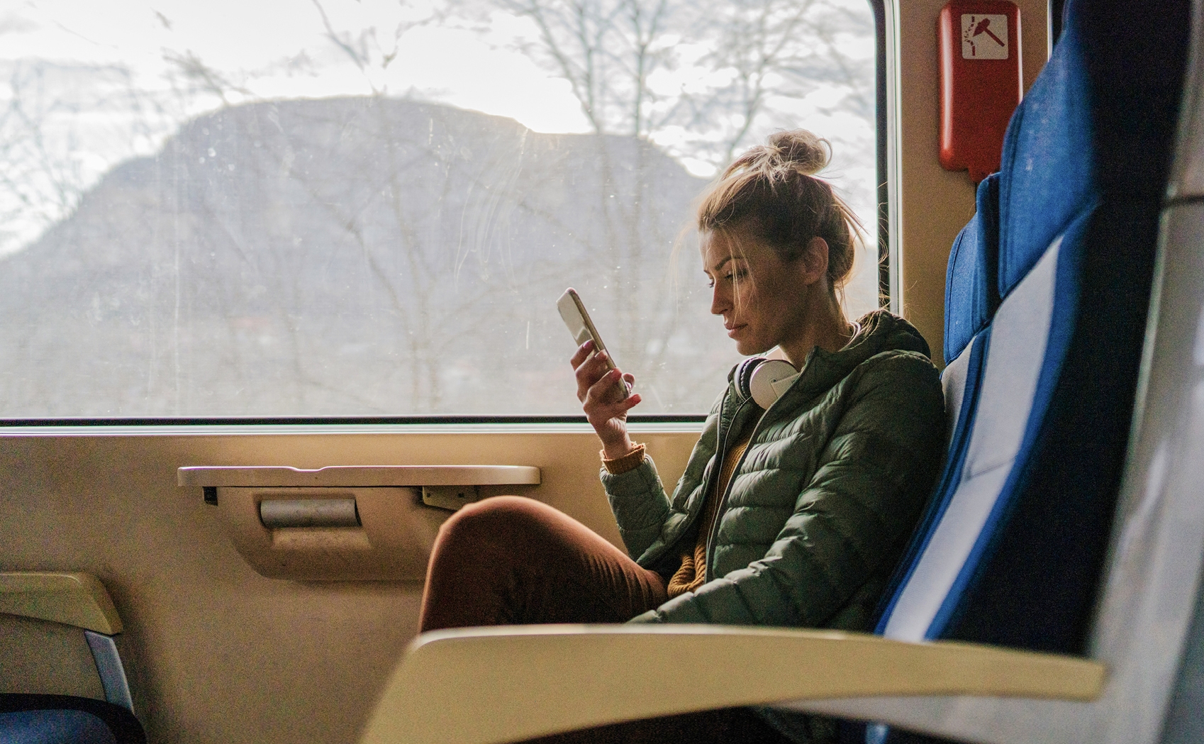 A woman sitting on a train, looking at her phone