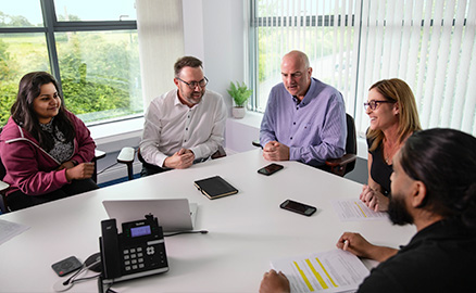 5 office workers round a table drafting their sustainability strategy