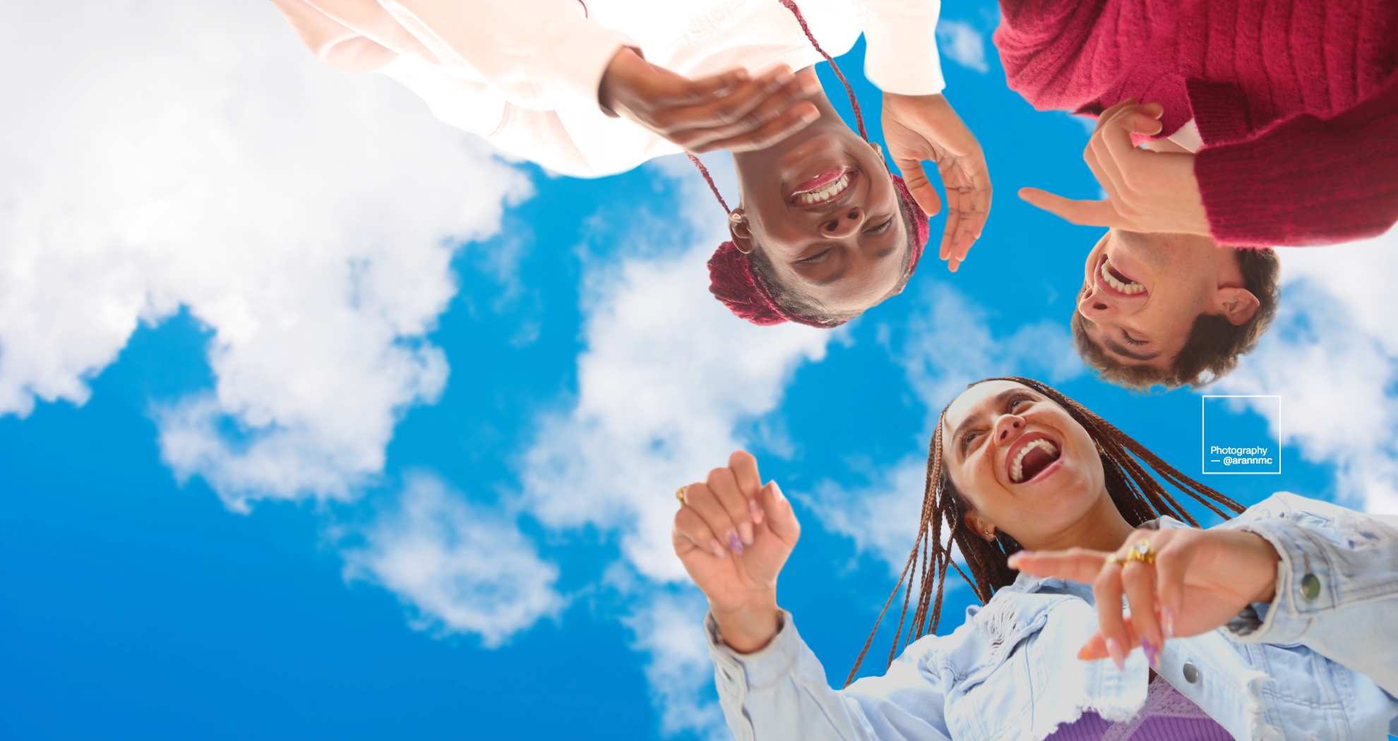 A group of children laughing with eah other with the sky pictured above them